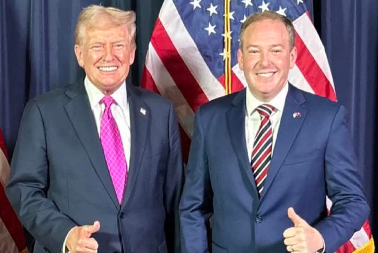 Donald Trump y Lee Zeldin sonriendo y levantando el pulgar con la bandera de Estados Unidos detrás. 