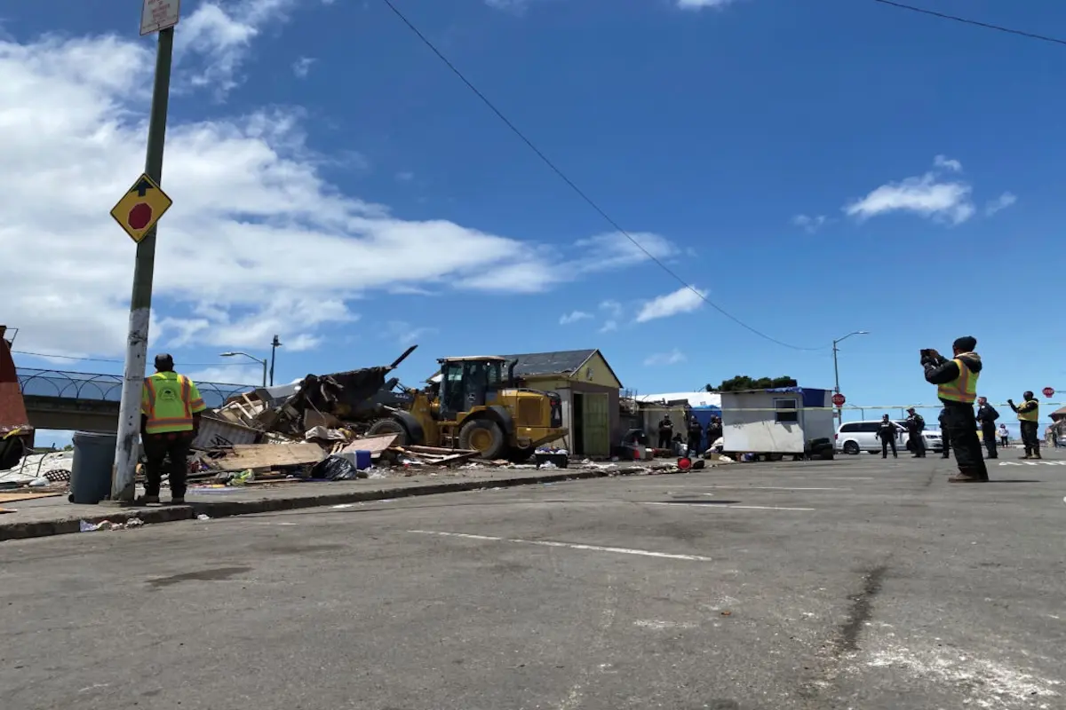 En las redadas de personas sin hogar y en la represión militarizada contra los inmigrantes, se están destruyendo los derechos de grupos ya marginados. El equipo de gestión de campamentos de Oakland derriba una hilera de edificios de madera en East 12th Street, el 12 de mayo de 2025. Foto de Bradley Penner.