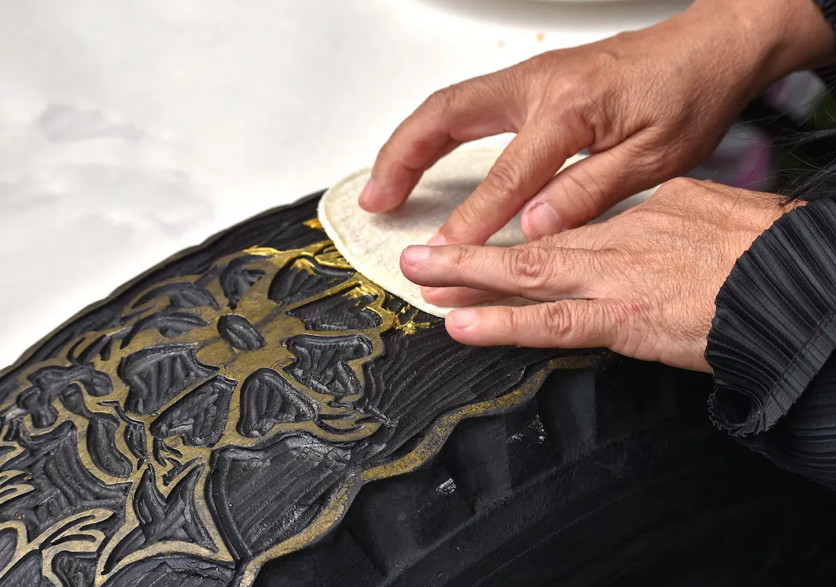 Se aplicó pintura no tóxica sobre las imágenes de ramas y flores talladas por Romero en la goma del neumático. Luego, tomó una tortilla de maíz, la presionó sobre la superficie y, tras despegarla, copió la imagen de una flor dorada.