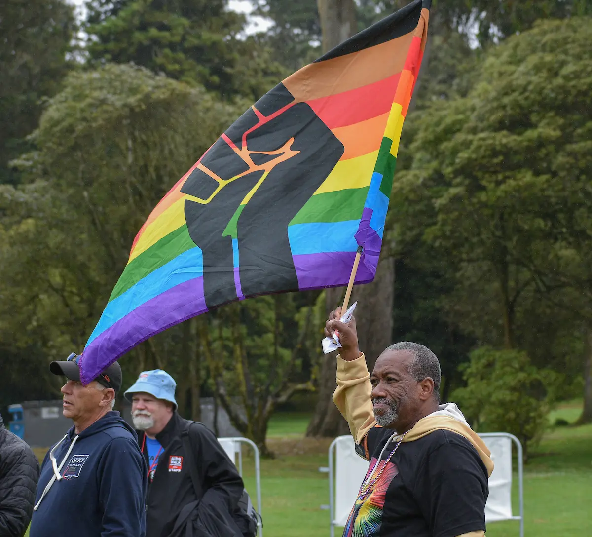 Tyree Leslie sostiene una bandera del orgullo con un puño estampado antes de unirse a su equipo en la Caminata anual contra el SIDA "AIDS Walk San Francisco", celebrada en el Golden Gate Park de San Francisco, California, el domingo 20 de julio de 2025. Foto: Andres Jimenez Larios / Bay City News