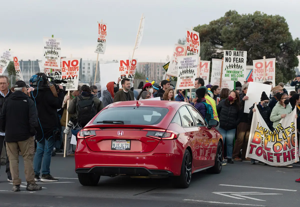 Un numeroso grupo de manifestantes intenta bloquear la entrada a la isla de la guardia costera en Alameda, en Oakland (California), el jueves 23 de octubre de 2025, en medio de los planes para aumentar la presencia de agentes federales en el área de la bahía, solicitada por el presidente Donald Trump. (Andrés Jiménez Larios/Bay City News)