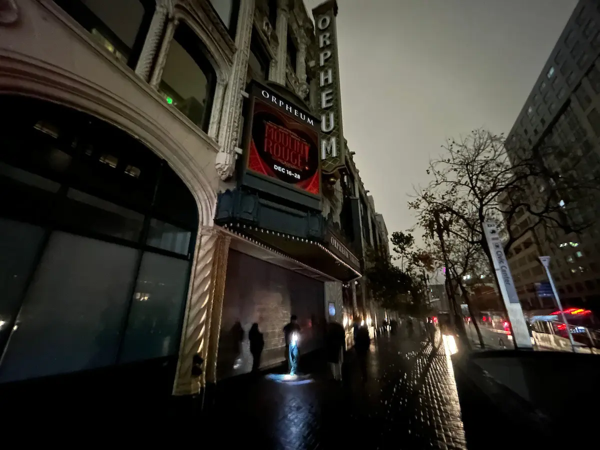 Los cortes de energía de diciembre renovaron el interés de los supervisores en el esfuerzo de que San Francisco adquiera los activos de PG&E en la ciudad. Foto: Peatones caminan por un sendero oscuro frente al Teatro Orpheum, en la calle Market de San Francisco, California, a las 7:15 p. m. del sábado 20 de diciembre de 2025, durante un apagón que afectó a unos 130 mil clientes en toda la ciudad. (Thomas Hughes/Bay City News)
