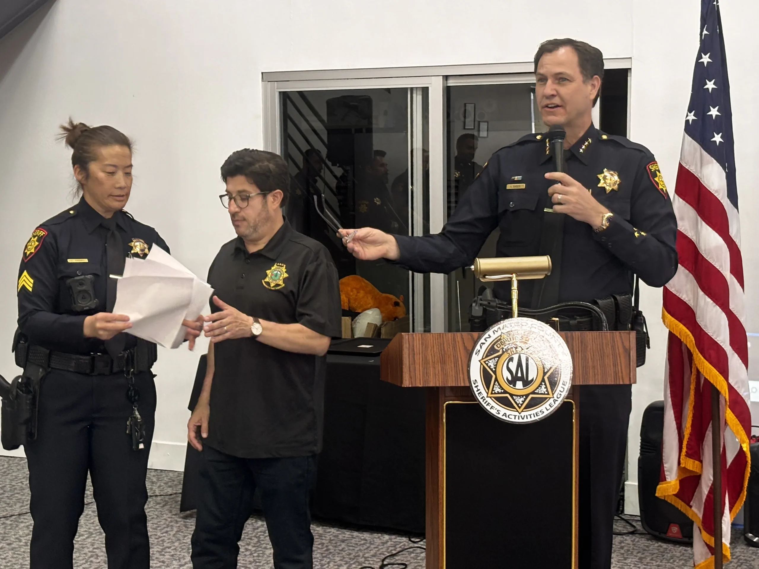 Habla a los presentes el Sheriff Ken Binder. A la izquierda la sargento Lilian Tashiro de la Unidad Comunitaria - Oficina del Alguacil, y el administrador de CARON José Luis Aguirre.