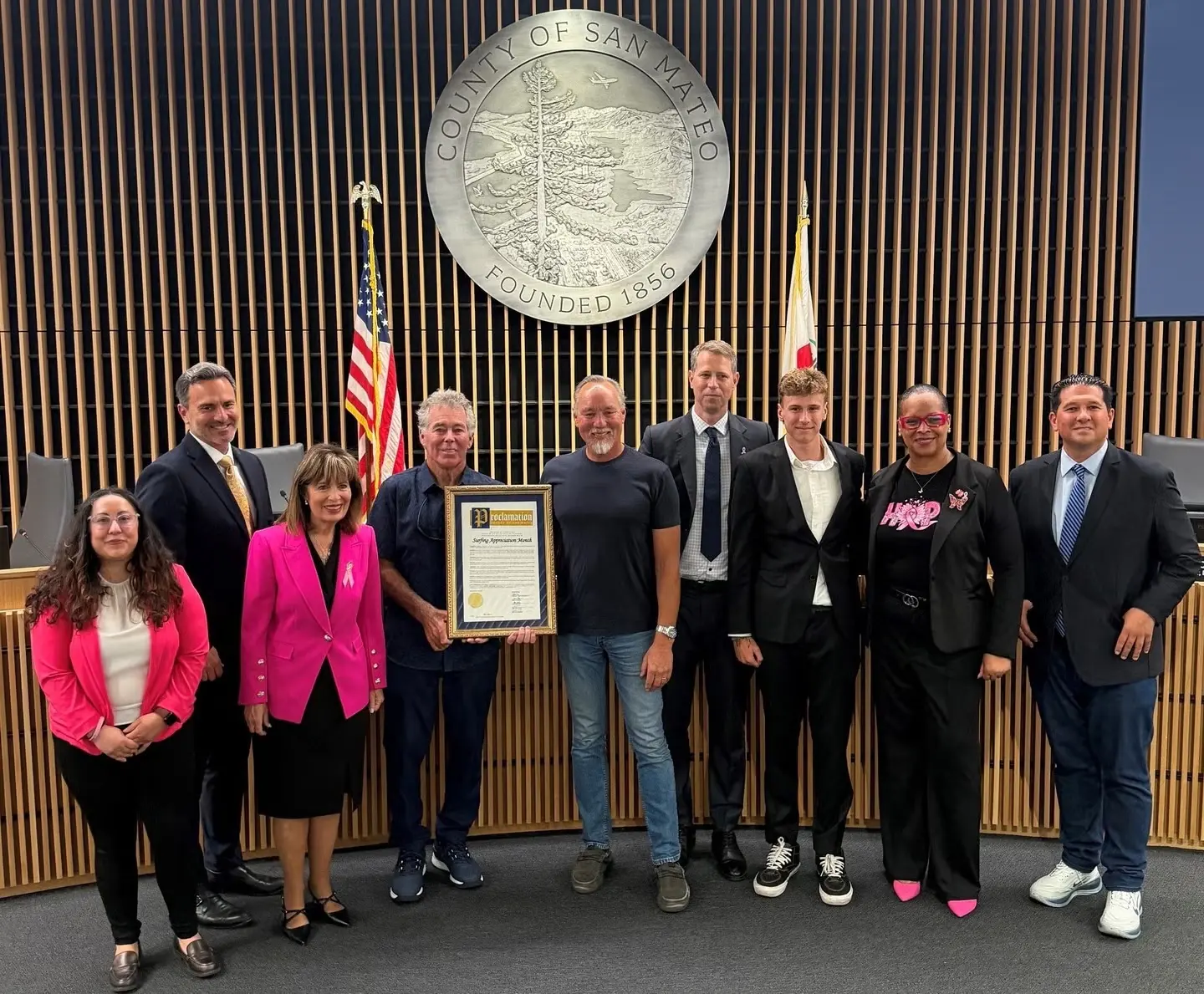 La Junta de Supervisores proclama octubre de 2026 como el Mes de Apreciación del Surf. De izquierda a derecha: la presidenta de la Junta, Noelia Corzo; los supervisores Ray Mueller y Jackie Speier; Jeff Clark; Marty Phelps; el subdirector ejecutivo del condado, Adam Ely; Liam Ely; y los supervisores Lisa Gauthier y David Canepa.